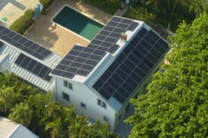 Casa com painéis solares no telhado vista de cima, ao lado de uma piscina.