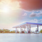 Posto de combustíveis ao ar livre com céu azul e algumas nuvens ao fundo.