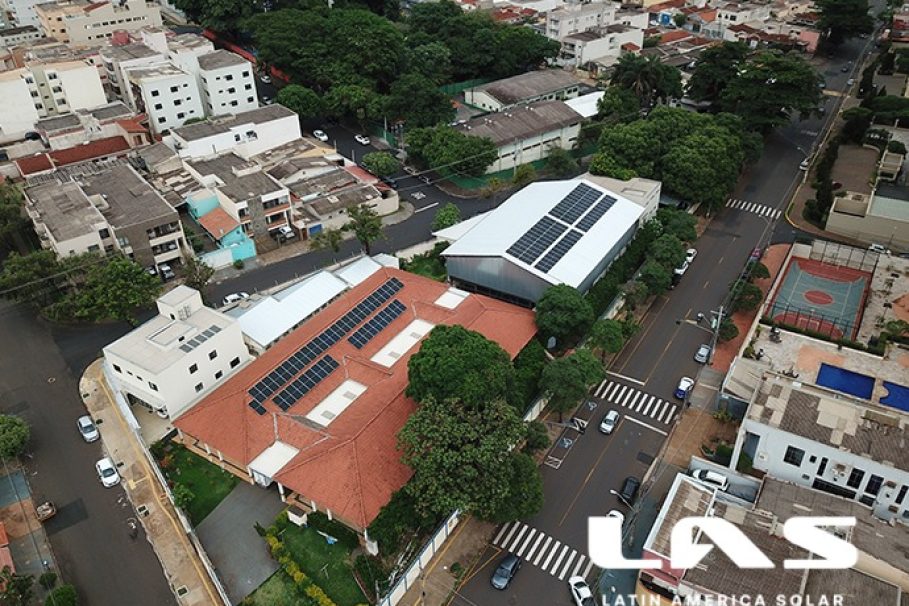 Adevirp Vista aérea de um bairro urbano com prédios e casas, destacando construções com painéis solares nos telhados.