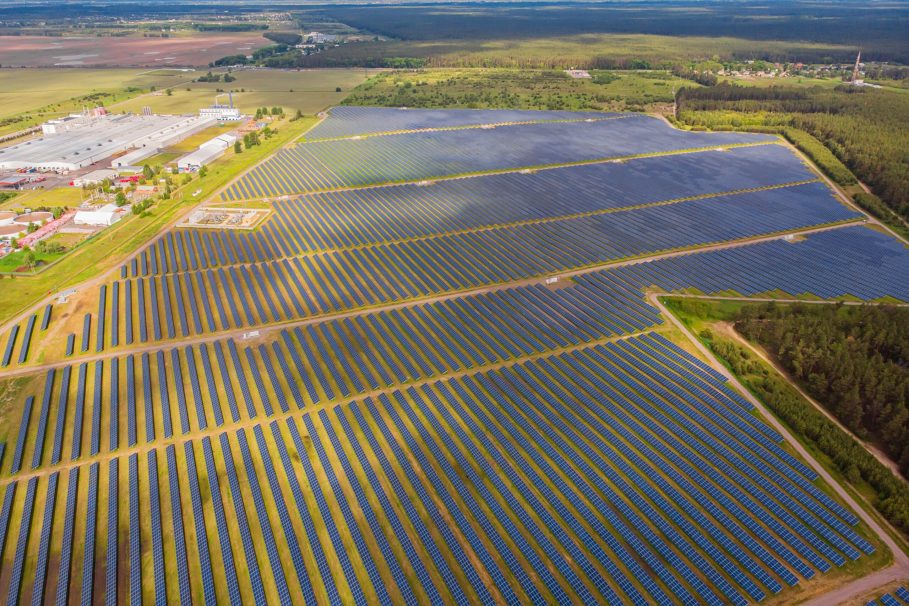 Solar power plant in the field. Aerial view of Solar panels. Vista aérea de uma grande usina de energia solar com milhares de painéis solares alinhados em fileiras sobre um campo extenso.
